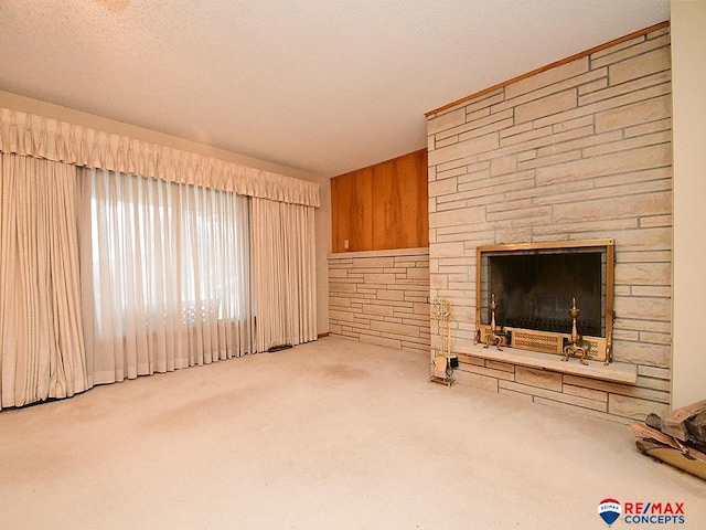 unfurnished living room featuring light carpet, a textured ceiling, and wood walls