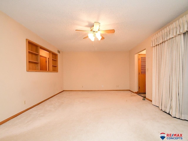 carpeted spare room featuring ceiling fan, a textured ceiling, and built in shelves