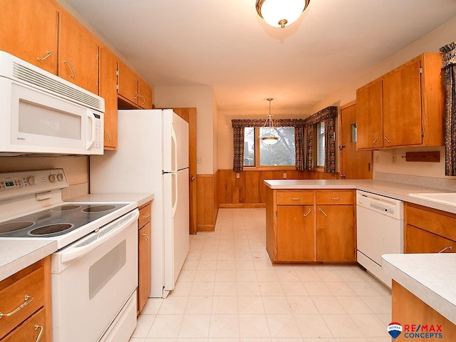 kitchen with white appliances, decorative light fixtures, kitchen peninsula, and wood walls