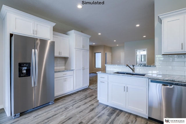 kitchen with white cabinetry, sink, stainless steel appliances, and light stone countertops