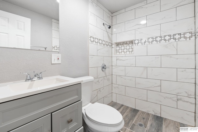 bathroom featuring vanity, tiled shower, and toilet