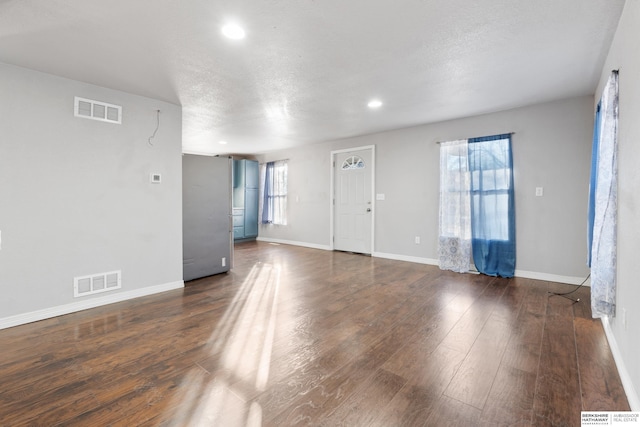 unfurnished living room featuring dark hardwood / wood-style flooring, a textured ceiling, and a wealth of natural light