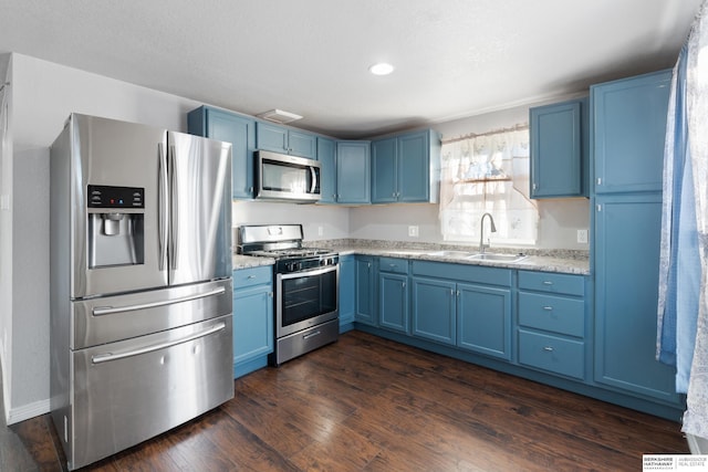 kitchen with blue cabinetry, appliances with stainless steel finishes, dark hardwood / wood-style floors, and sink