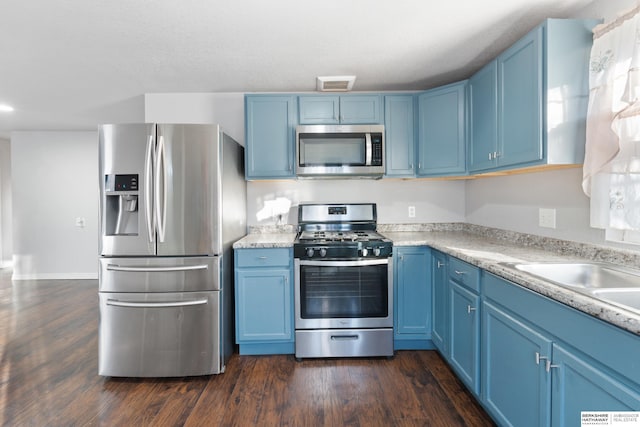 kitchen featuring dark wood-type flooring, blue cabinetry, and appliances with stainless steel finishes