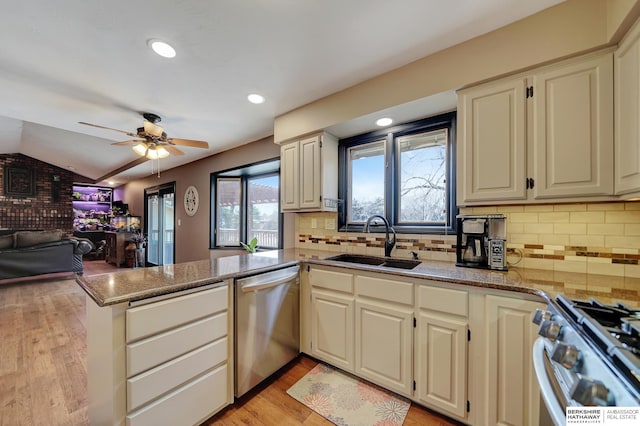 kitchen with sink, light stone countertops, kitchen peninsula, and appliances with stainless steel finishes