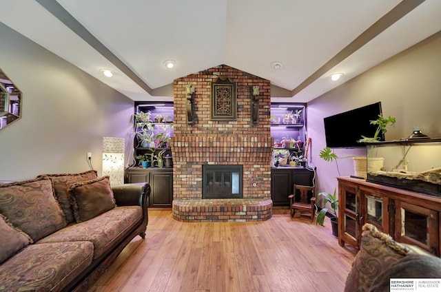 living room with lofted ceiling, a fireplace, and light hardwood / wood-style floors