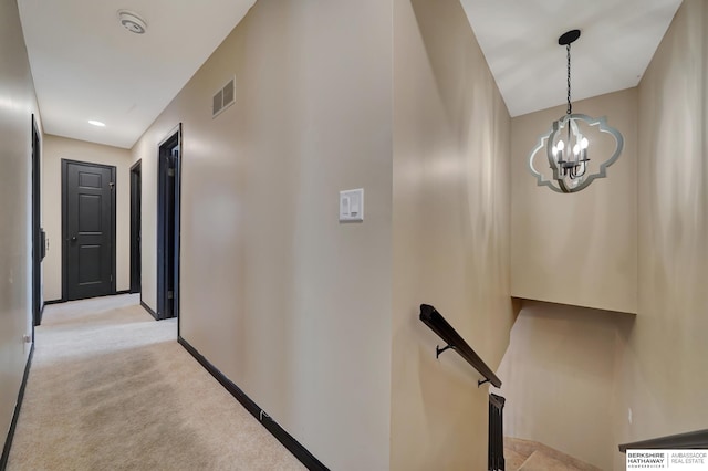 hallway with a chandelier and light carpet