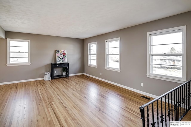 unfurnished living room with a textured ceiling and light wood-type flooring