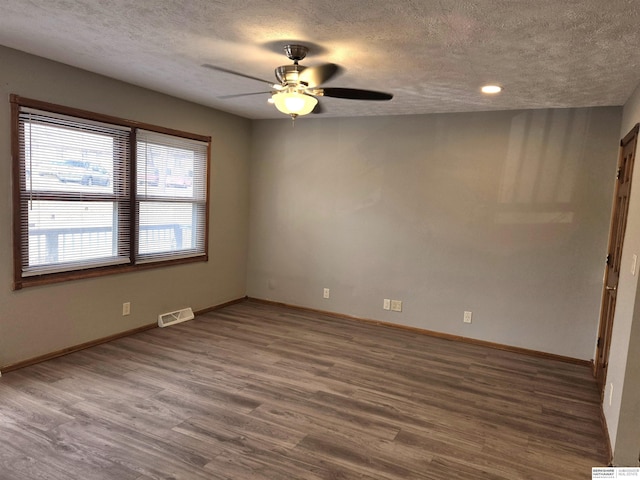 spare room with dark hardwood / wood-style flooring, ceiling fan, and a textured ceiling