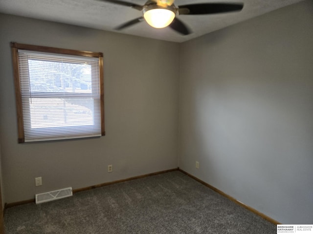 spare room with ceiling fan and dark colored carpet