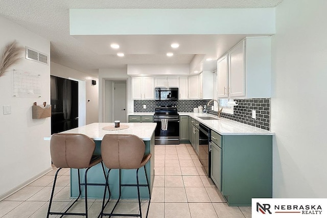 kitchen featuring sink, black appliances, a center island, decorative backsplash, and white cabinets