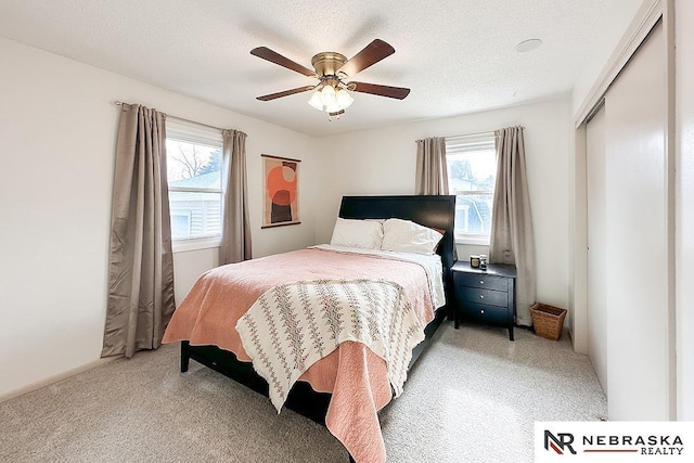 bedroom with multiple windows, light colored carpet, a closet, and a textured ceiling