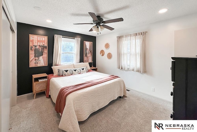 bedroom with ceiling fan, light colored carpet, and a textured ceiling