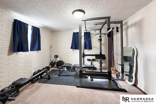 exercise room with brick wall and a textured ceiling