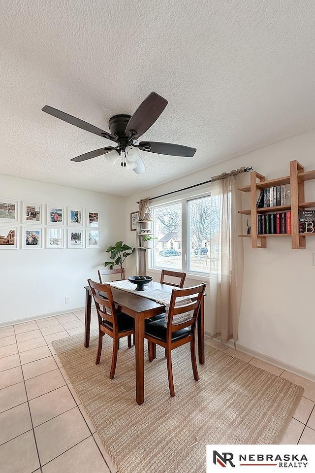 tiled dining space with ceiling fan and a textured ceiling