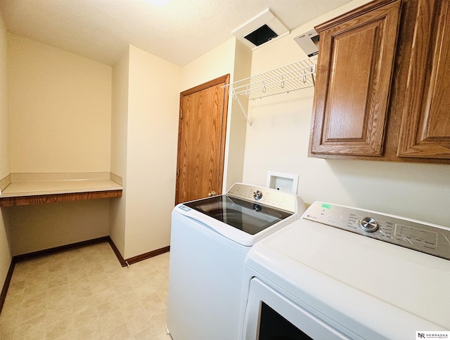 washroom featuring cabinets, washing machine and clothes dryer, and a textured ceiling