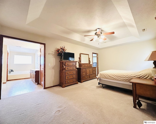 bedroom with light carpet, ceiling fan, a tray ceiling, and a textured ceiling