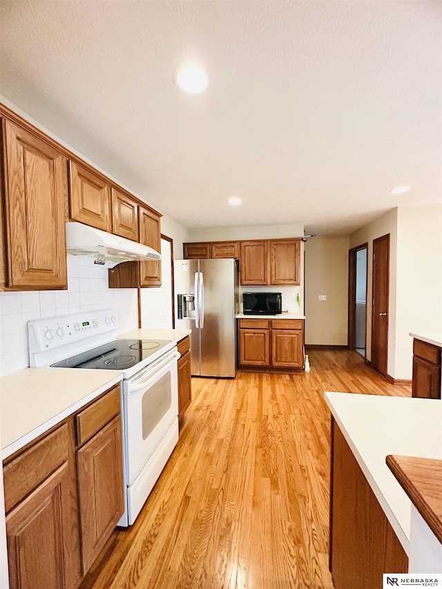 kitchen with light hardwood / wood-style flooring, decorative backsplash, stainless steel fridge, and white electric range oven