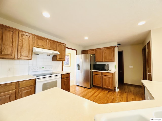 kitchen with electric stove, decorative backsplash, stainless steel fridge, and light hardwood / wood-style flooring