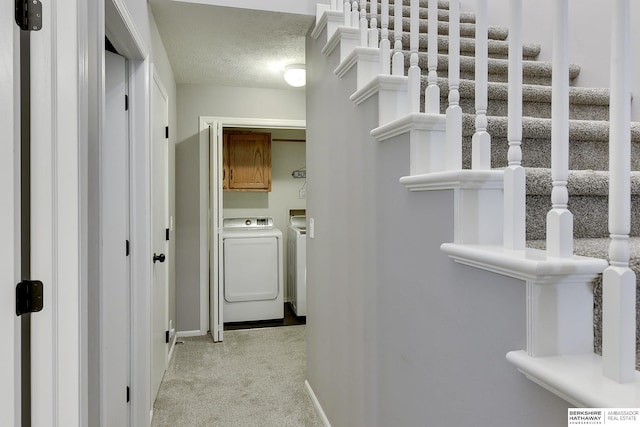 corridor with light colored carpet, separate washer and dryer, and a textured ceiling