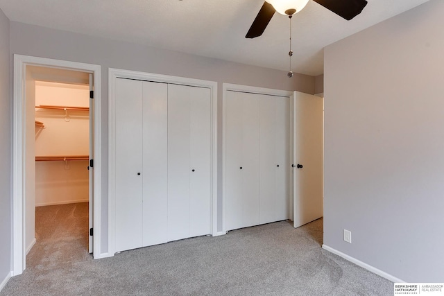 unfurnished bedroom with two closets, light colored carpet, and ceiling fan