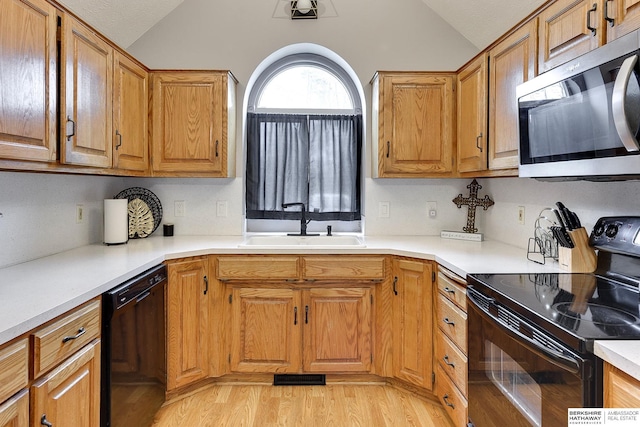 kitchen with lofted ceiling, light hardwood / wood-style floors, sink, and black appliances