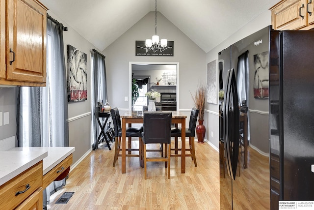 dining space featuring an inviting chandelier, vaulted ceiling, and light hardwood / wood-style floors