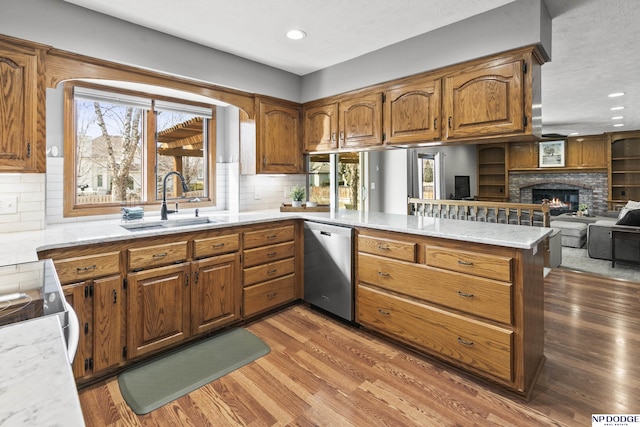 kitchen featuring stainless steel dishwasher, sink, kitchen peninsula, and hardwood / wood-style floors