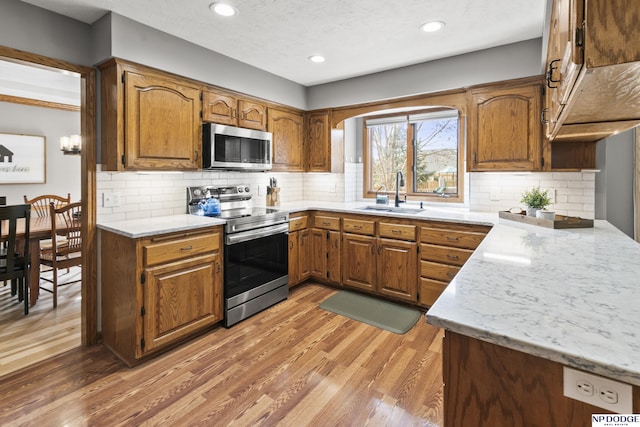 kitchen with wood-type flooring, sink, backsplash, stainless steel appliances, and a textured ceiling