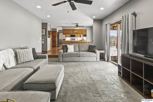 carpeted living room featuring ceiling fan and a textured ceiling