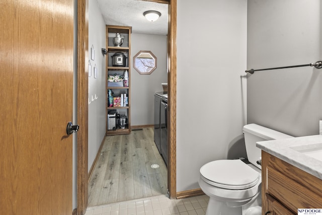 bathroom with vanity, wood-type flooring, a textured ceiling, washing machine and clothes dryer, and toilet