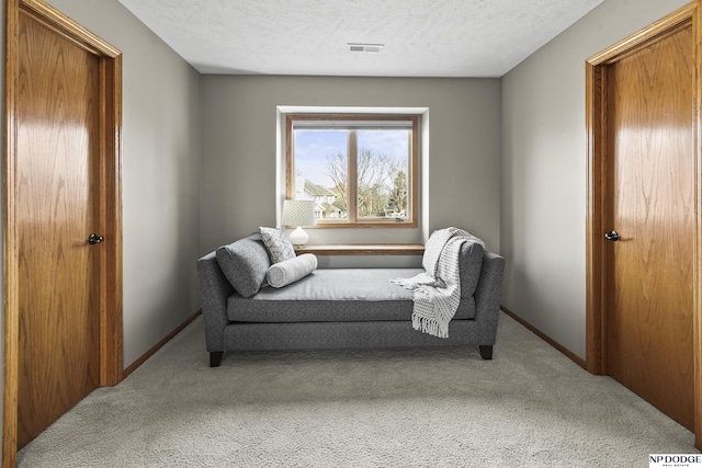 living area with light carpet and a textured ceiling