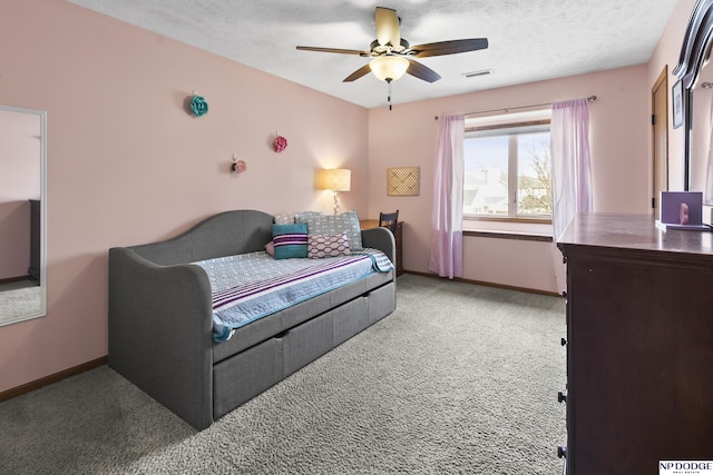 carpeted bedroom featuring ceiling fan and a textured ceiling