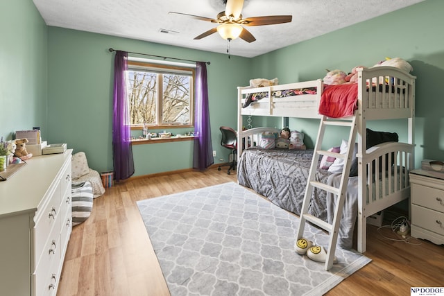 bedroom featuring ceiling fan, light hardwood / wood-style floors, and a textured ceiling