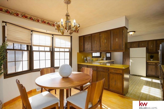 dining room featuring an inviting chandelier, sink, and light wood-type flooring