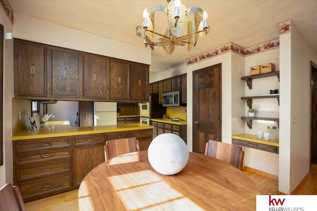 kitchen with pendant lighting, sink, white refrigerator, dark brown cabinetry, and oven