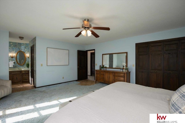 bedroom featuring light carpet, connected bathroom, a closet, and ceiling fan