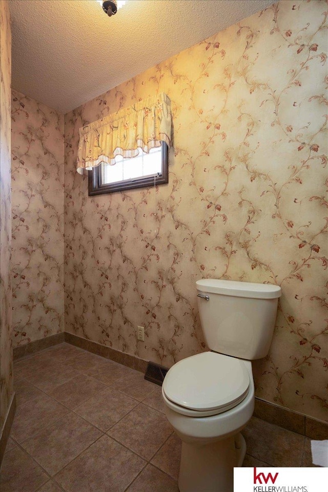 bathroom with tile patterned flooring, toilet, and a textured ceiling