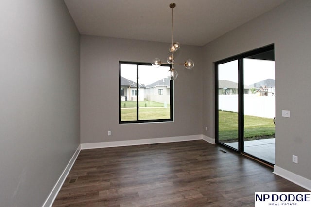 unfurnished dining area featuring a notable chandelier, a wealth of natural light, and dark wood-type flooring