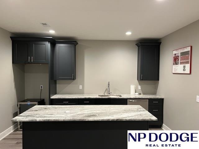 kitchen featuring light stone counters, stainless steel dishwasher, sink, and a kitchen island