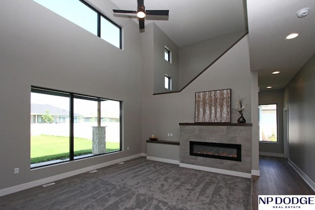 unfurnished living room featuring dark hardwood / wood-style flooring, a tile fireplace, and a healthy amount of sunlight