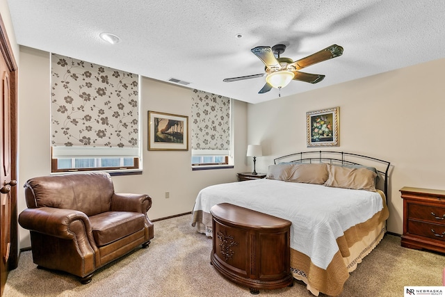 carpeted bedroom featuring ceiling fan and a textured ceiling