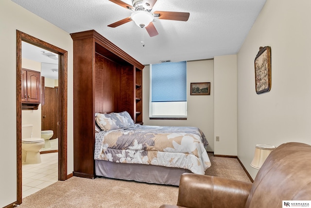 bedroom with ceiling fan, light colored carpet, a textured ceiling, and ensuite bathroom