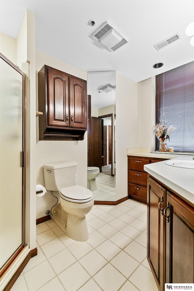 bathroom with a shower with door, vanity, tile patterned flooring, and toilet