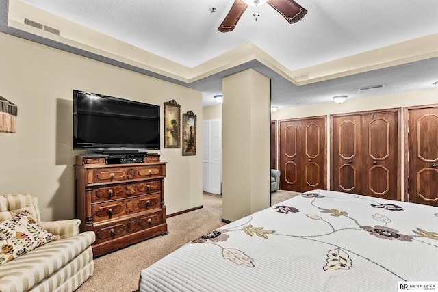 carpeted bedroom featuring ceiling fan and a textured ceiling