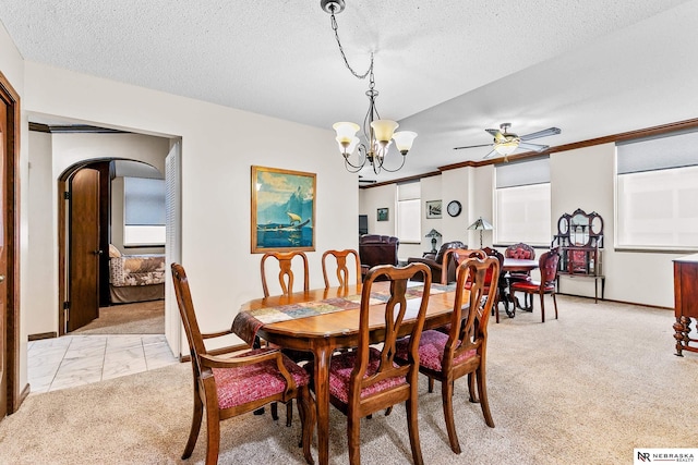 carpeted dining room with ceiling fan with notable chandelier and a textured ceiling