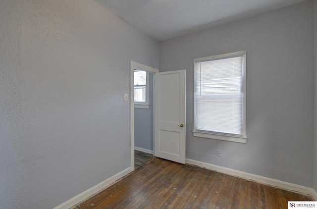 empty room with dark wood-style flooring and baseboards