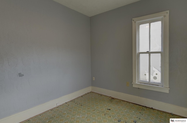 empty room featuring a wealth of natural light, baseboards, and tile patterned floors