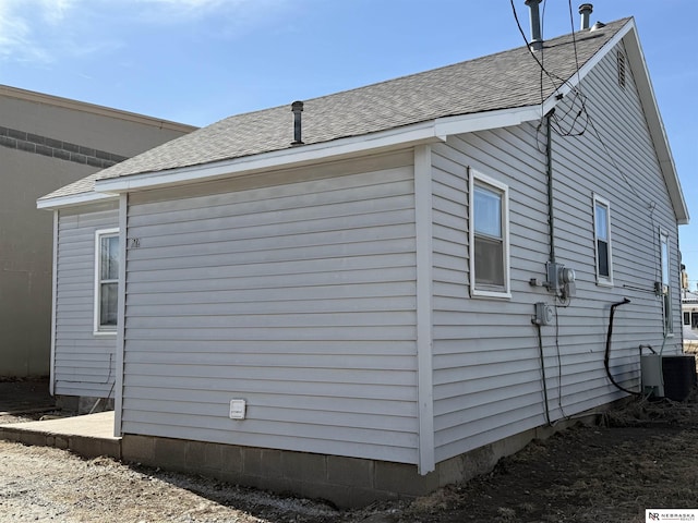 view of side of property with a shingled roof and central AC unit