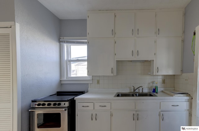 kitchen featuring tasteful backsplash, white cabinets, stainless steel range with electric cooktop, and a sink